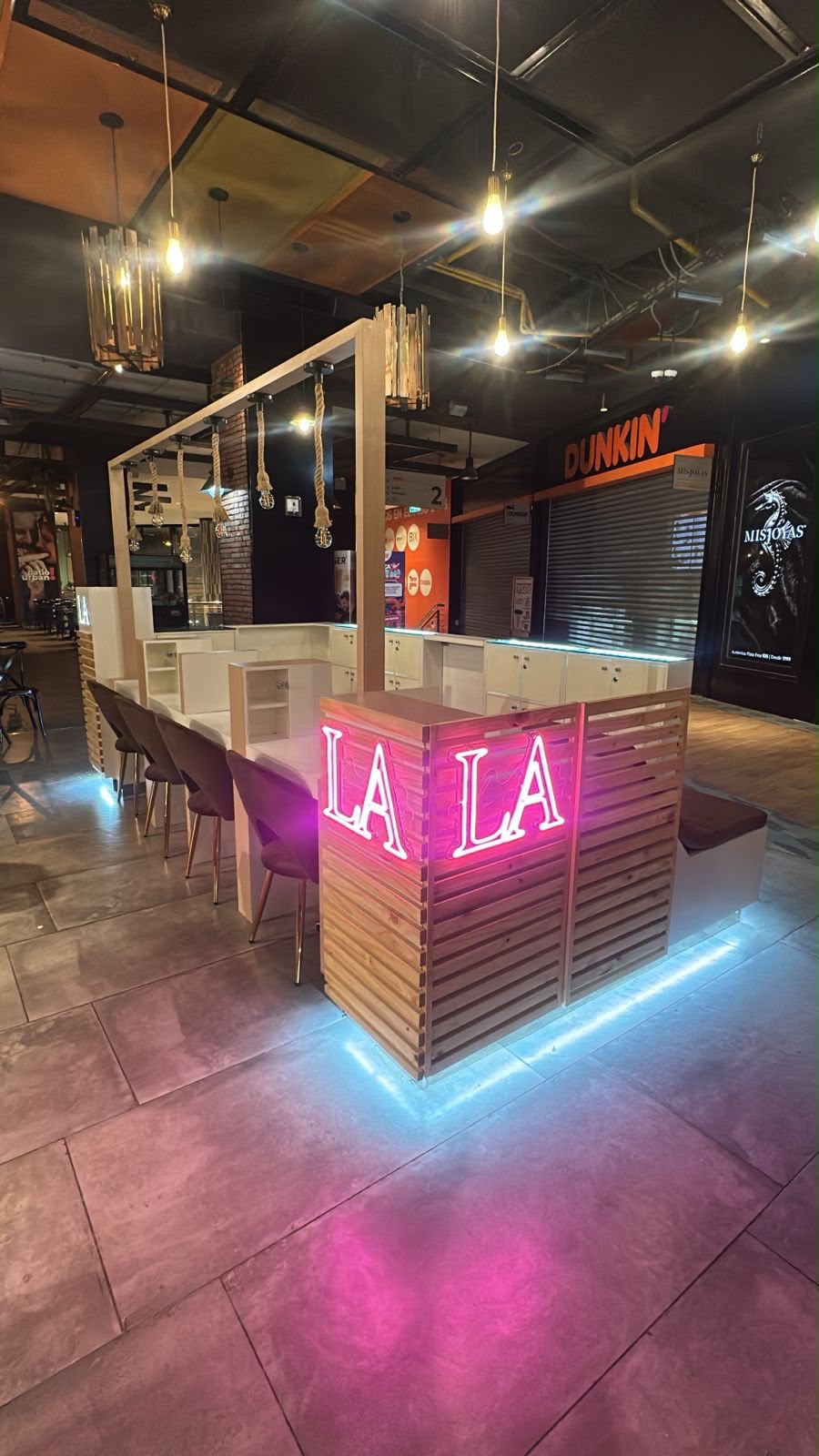 Módulo comercial visto en diagonal, con letrero luminoso, estructura de madera y mobiliario blanco